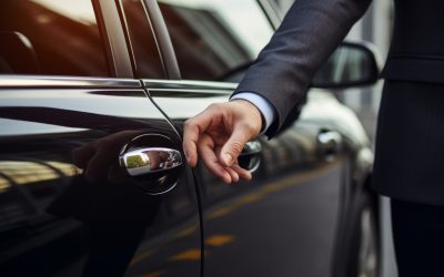 A businessman's hand reaches for the door of a luxury car. Background with selective focus and copy space